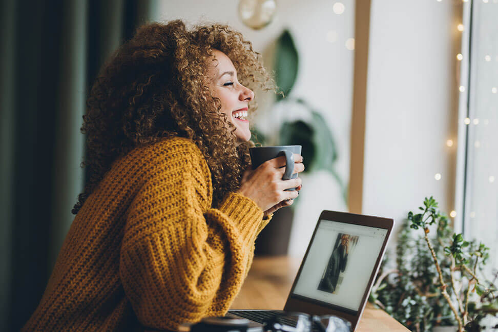 Smiling freelancer working with a coffee cup in hand