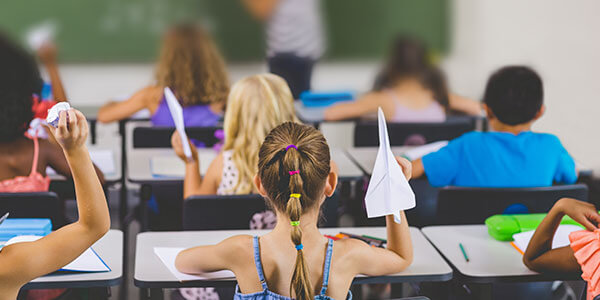 Class pupils throwing paper aeroplanes. Insurance advice for teachers.