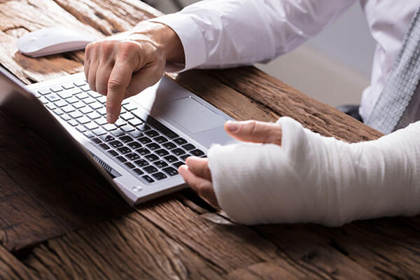 Man with broken wrist at laptop_Image used under licence from Shutterstock Image used under licence from Shutterstock