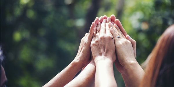 A group of hands high five each other to represent the teamwork involved in charity work